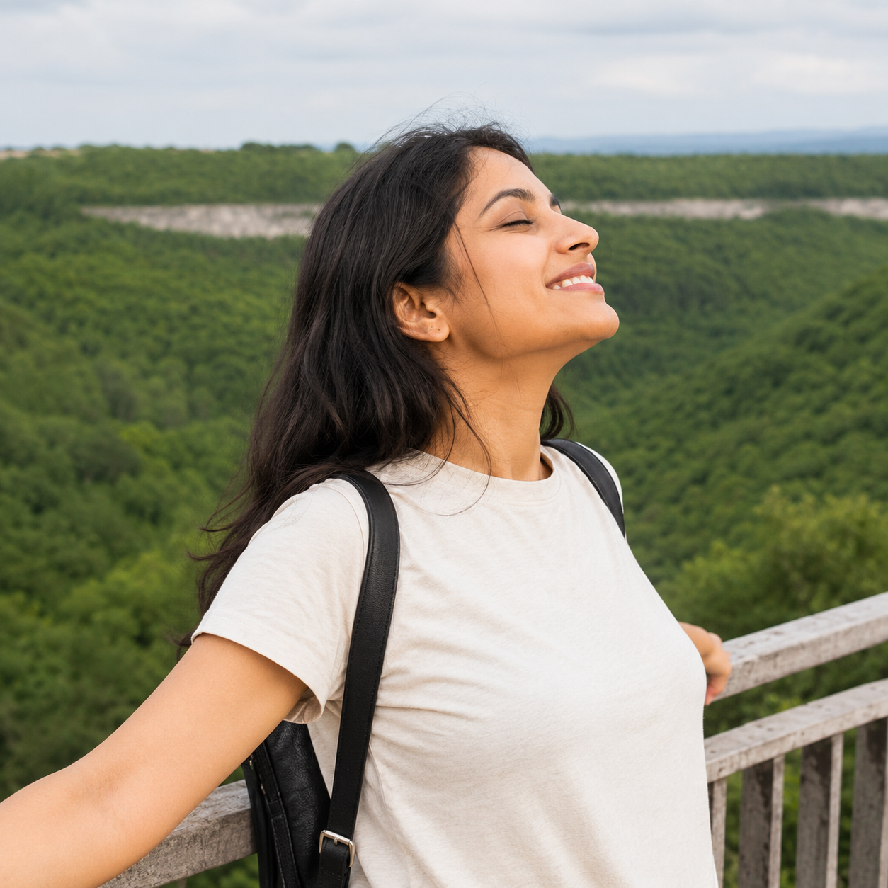 Woman standing peacefully in a green field with eyes closed